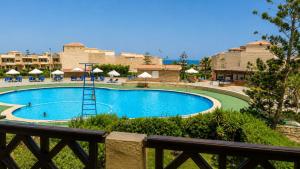 a swimming pool in a resort with chairs and umbrellas at فيلا لؤلؤة كرير عائلات فقط أو بنات in Sidi Kirayr