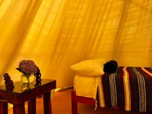 a bedroom with a bed and a table with a vase of flowers at Tipis Cuetzalan in Cuetzalán del Progreso
