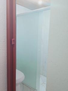 a bathroom with a toilet and a glass shower door at Garcia Suite 2 in Blumenau
