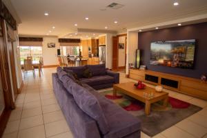 a living room with a purple couch and a tv at Thicker Than Water Vineyard - 4 Bedroom Pool in McLaren Vale