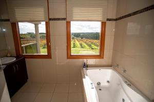 a bathroom with a tub and a sink and two windows at Thicker Than Water Vineyard - 4 Bedroom Pool in McLaren Vale +19 photos