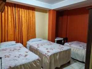 two beds in a room with orange walls at Hostal paris in Nazca