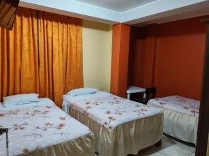 two beds in a room with orange curtains at Hostal paris in Nazca