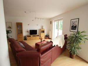 a living room with a leather couch and a tv at Appartement im Seedomizil Kummerow in Kummerow