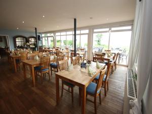 a restaurant with wooden tables and chairs and windows at Appartement im Seedomizil Kummerow in Kummerow