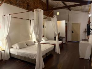a bedroom with two beds with white curtains at Casa Lavinia in São Luís