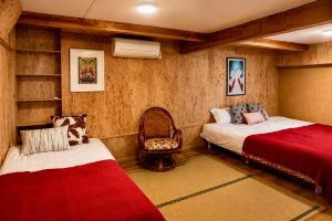 a bedroom with two beds and a chair at Alley Oop Hakuba in Hakuba