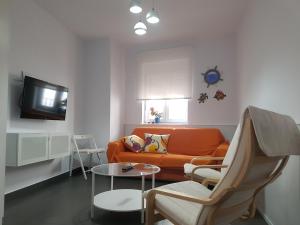 sala de estar con sofá naranja y mesa en Casa Salmonete 8, en Conil de la Frontera