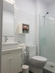 Baño blanco con aseo y lavamanos en Casa Salmonete 8, en Conil de la Frontera