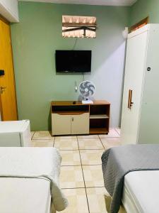 a bedroom with two beds and a flat screen tv at quarto aconchegou 1 in Divinópolis