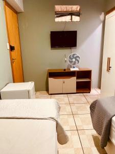 a room with a tv and a room with two beds at quarto aconchegou 1 in Divinópolis