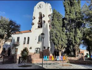 a building with a clock tower with a sign in front at Urku Runa in Humahuaca