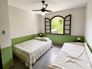 a bedroom with two beds and a window at Recanto Dom José in Peruíbe +5 photos