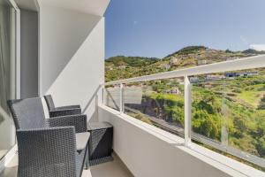 a balcony with two chairs and a view of a hill at Atlantic Dutchman Heated Pool & Parking in Caniço