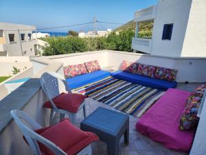 a patio with a couch and chairs on a balcony at Villa SiJoBa in Raʼs al Jabal