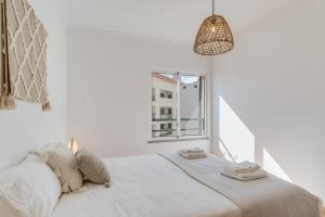 a white bedroom with a bed and a window at Alta Do Garajau I 5ºw in Caniço