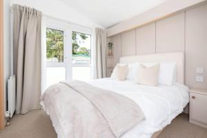 a white bedroom with a large white bed and a window at The Chester-2 bed Static Caravan in Oxnam