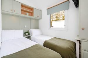 two beds in a small room with a window at The Chester-2 bed Static Caravan in Oxnam +20 photos