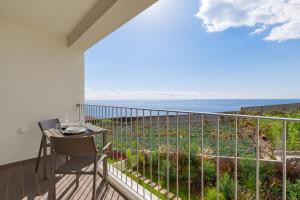 a balcony with a table and a view of the ocean at Pool Retreat For Families & Romantic Escapes in Câmara de Lobos
