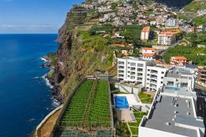 a view of the ocean and buildings on a cliff at Pool Retreat For Families & Romantic Escapes in Câmara de Lobos