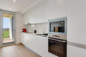 a kitchen with white walls and a large window at Pool Retreat For Families & Romantic Escapes in Câmara de Lobos +21 photos