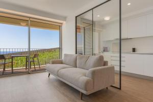 a living room with a couch and a balcony at Pool Retreat For Families & Romantic Escapes in Câmara de Lobos