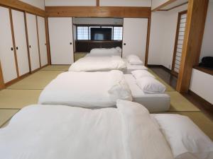 a row of white beds in a room at ASO Uchinomaki Stay in Aso