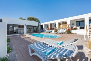 a patio with two lounge chairs and a swimming pool at Coast Unit 5, Bright Escape By Langebaan Lagoon in Langebaan