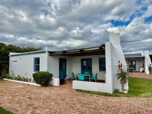 a white house with a table and chairs at Coast Cottages Langebaan in Langebaan
