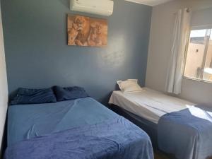 a bedroom with two beds and a window and a painting at Casa com Ar-Condicionado in Formosa
