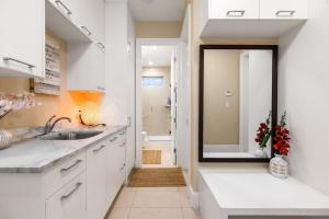 a white kitchen with a sink and a mirror at Sunnywood Garden in Richmond +14 photos