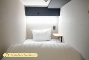 a bed with a white pillow in a small room at Luma Urban Hotel 高田馬場 in Tokyo