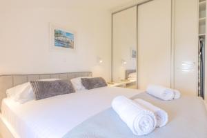 a bedroom with two beds with white sheets and towels at Gea Maris Apartment in Kaštela