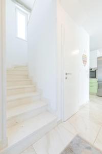 a white staircase in a white room with a door at Gea Maris Apartment in Kaštela