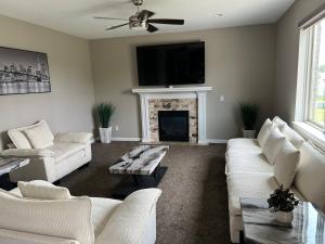 a living room with white furniture and a fireplace at Sterling Heights Retreat ! in Sterling Heights