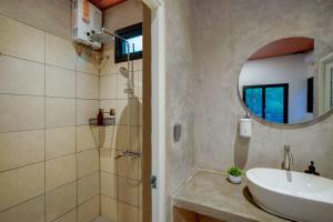 a bathroom with a sink and a shower with a mirror at Mariposa Cabin in Lembang