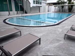 a swimming pool with two benches in front of a building at Chaidee Mansion in Bangkok