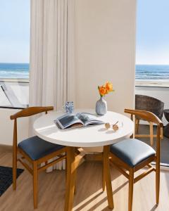 a white table with two chairs and a vase with flowers at Sandcastle Hotel on the Beach in Pismo Beach