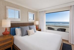 a bedroom with a bed with a view of the ocean at Sandcastle Hotel on the Beach in Pismo Beach