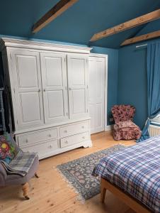 a bedroom with a large white cabinet and a chair at Rusthall Prospect House in Speldhurst