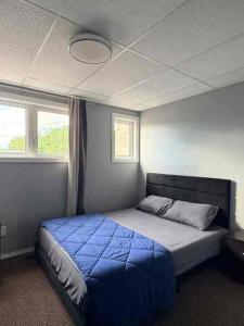 a bedroom with a bed with a blue comforter and two windows at 2806 Regina in Regina