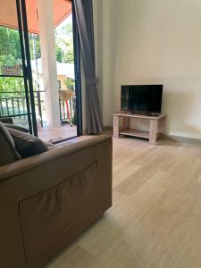 a living room with a couch and a flat screen tv at The Summer Cozy Cottage 2 in Haad Chao Phao