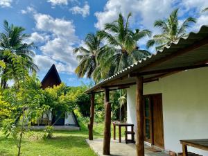a house with palm trees in the background at Cottage Paramount in Udawalawe