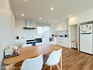 a kitchen with a wooden table and white appliances at Waterview Spacious Bliss - 2 Beds in Porirua