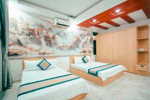 a bedroom with two beds and a painting on the wall at Khách sạn Chinh Thuỷ in Sầm Sơn +21 photos