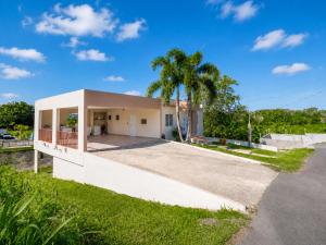 a white house with a palm tree and a driveway at Arenales Guest House in Isabela