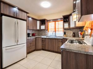 a kitchen with wooden cabinets and a white refrigerator at Arenales Guest House in Isabela