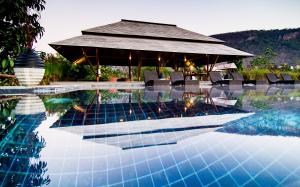 a pool with a pavilion and chairs and a house at Lala Mukha Tented Resort Khao Yai in Mu Si