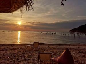 a beach with two chairs and the ocean at sunset at Umbrella tree เต้ทน์ in Nathon Bay