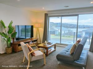 a living room with a couch and chairs and a tv at Waterview Spacious Bliss - 2 Beds in Porirua